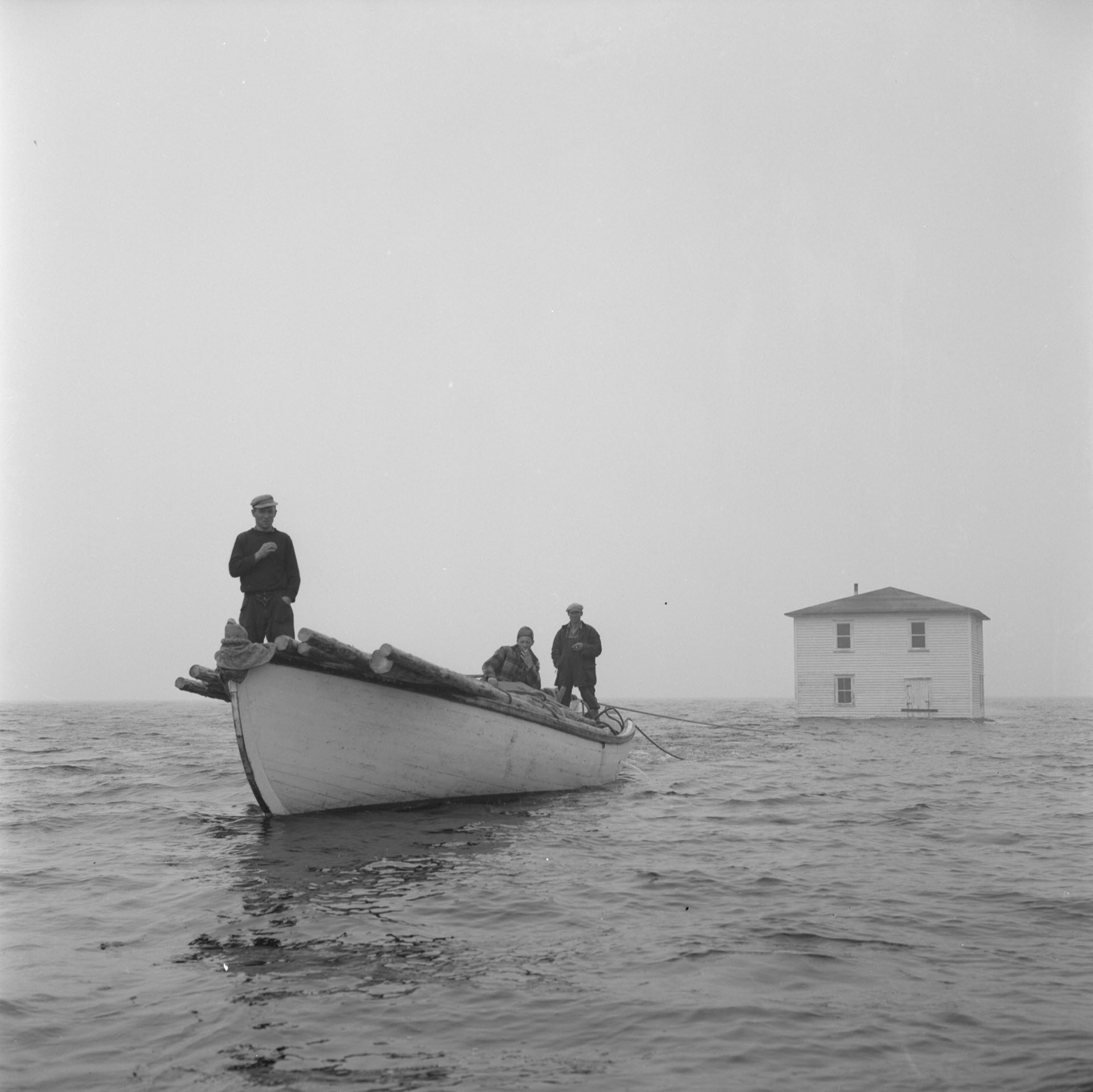 Newfoundland outport house being towed by fishing boat
